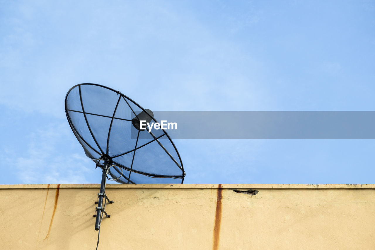 Black satellite disk on deck of building in sunny day