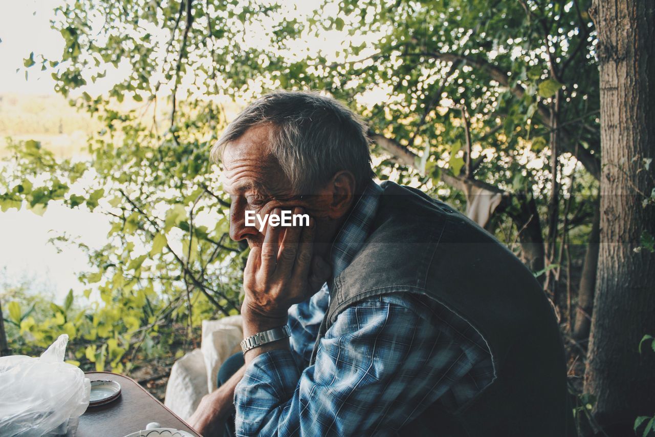 PORTRAIT OF MAN LOOKING AT CAMERA IN PARK