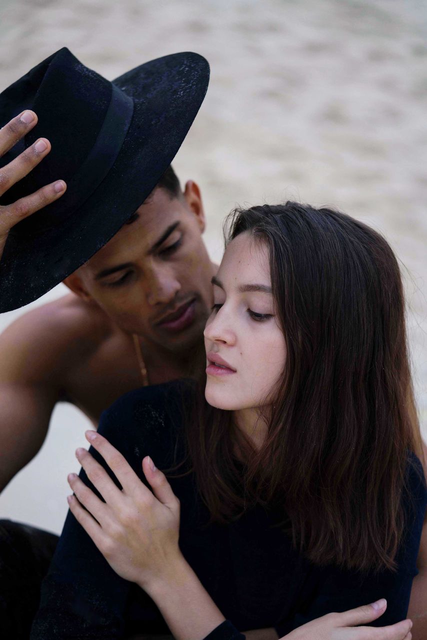 Portrait of young couple sitting in the beach together 