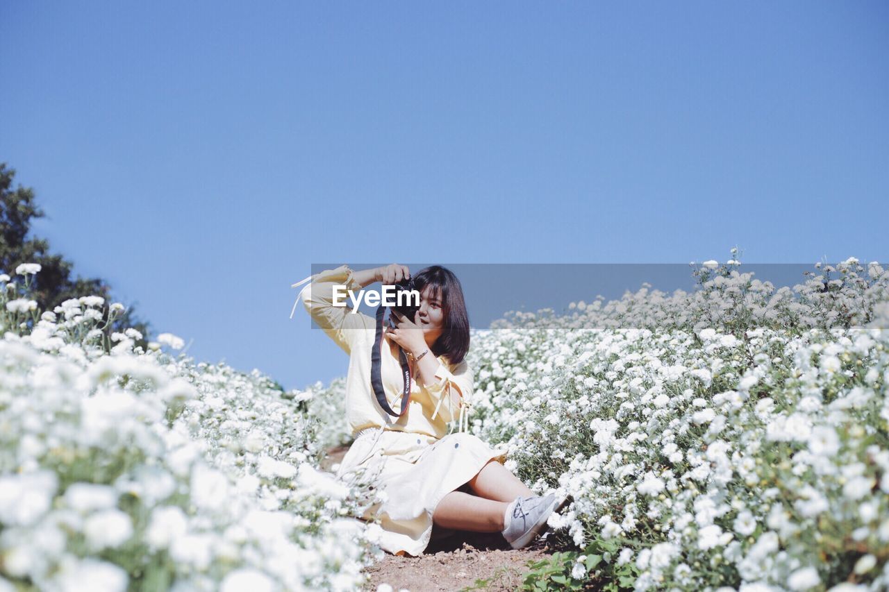 YOUNG WOMAN SITTING ON WHITE FLOWERS