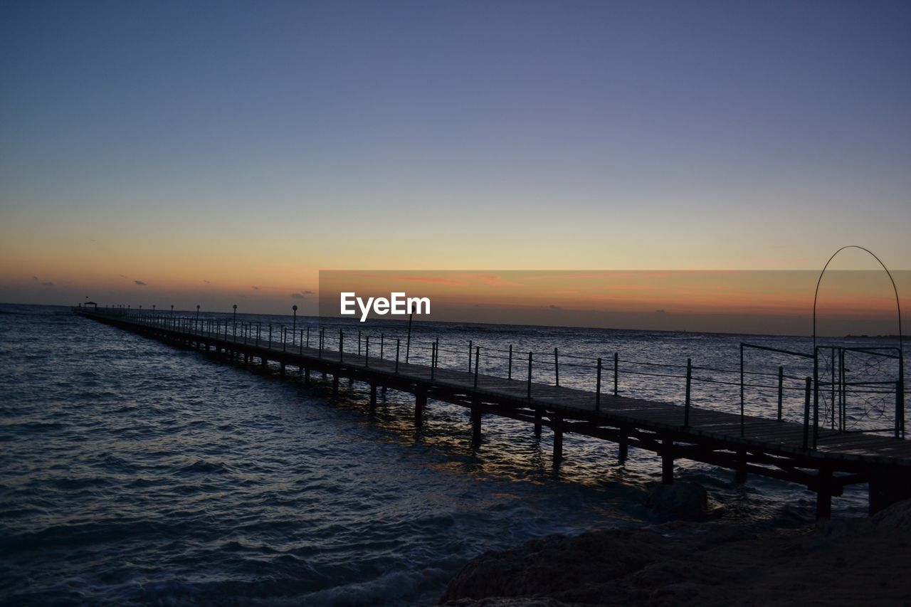 PIER OVER SEA AGAINST CLEAR SKY DURING SUNSET