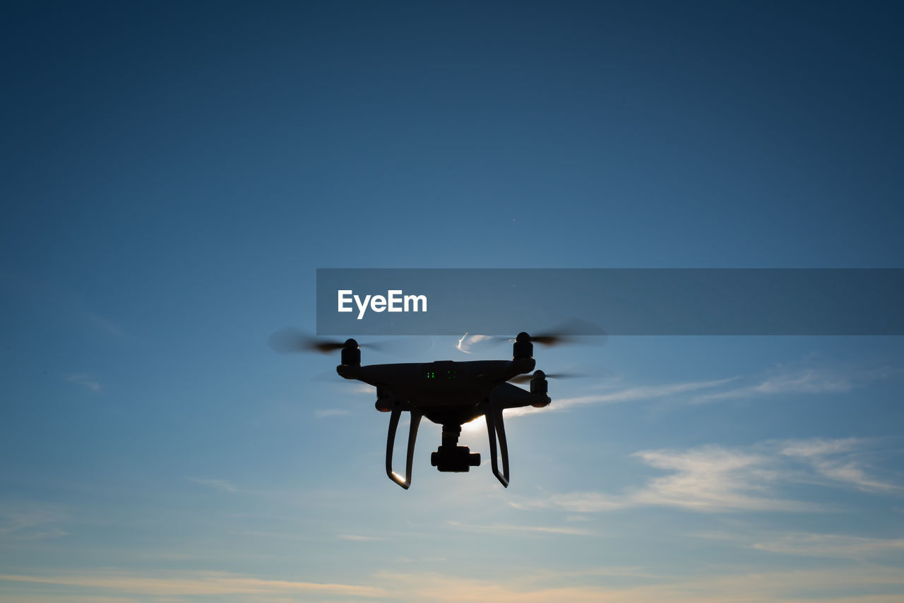 Low angle view of drone against blue sky