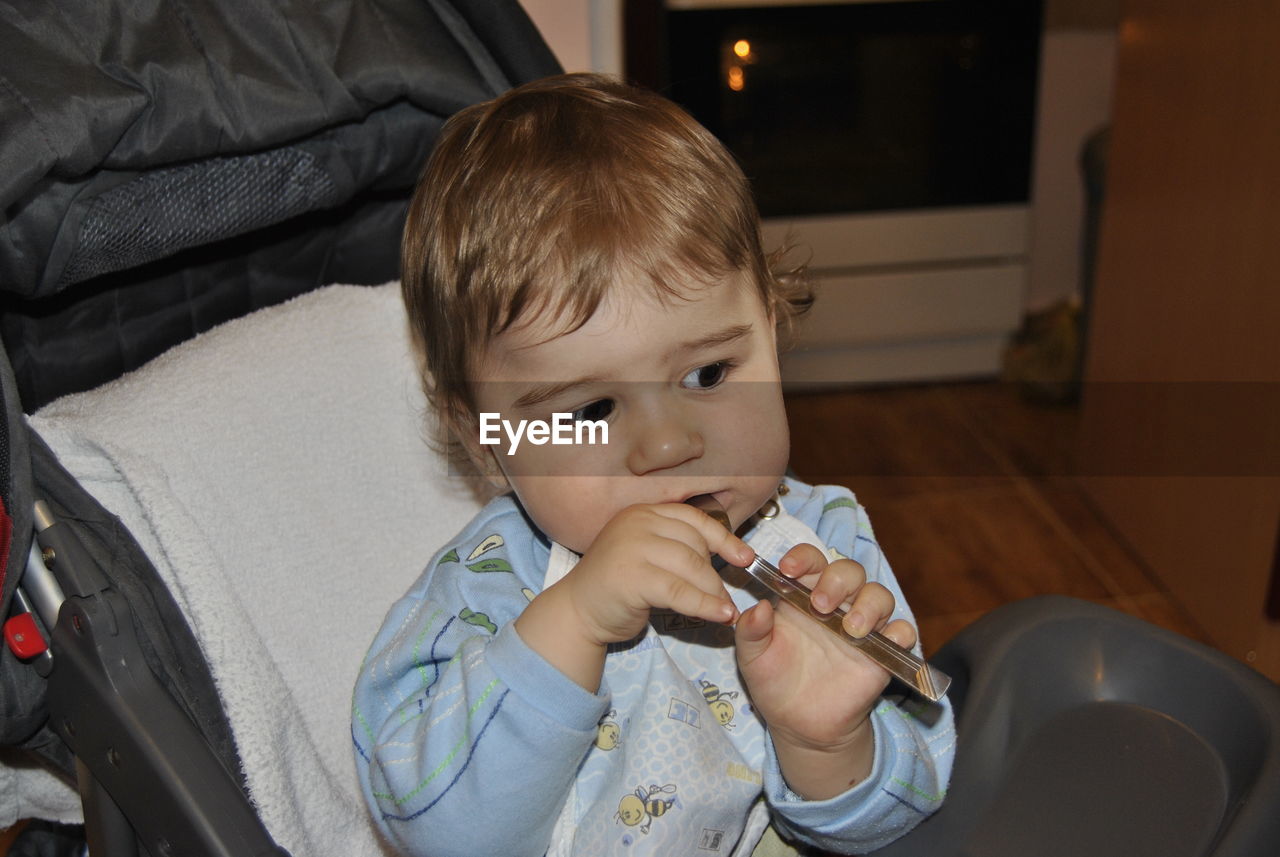 Close-up of cute boy playing with spoon at home