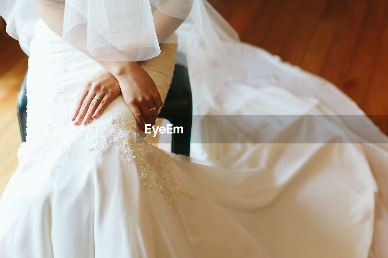 Midsection of bride sitting on stool in wedding ceremony