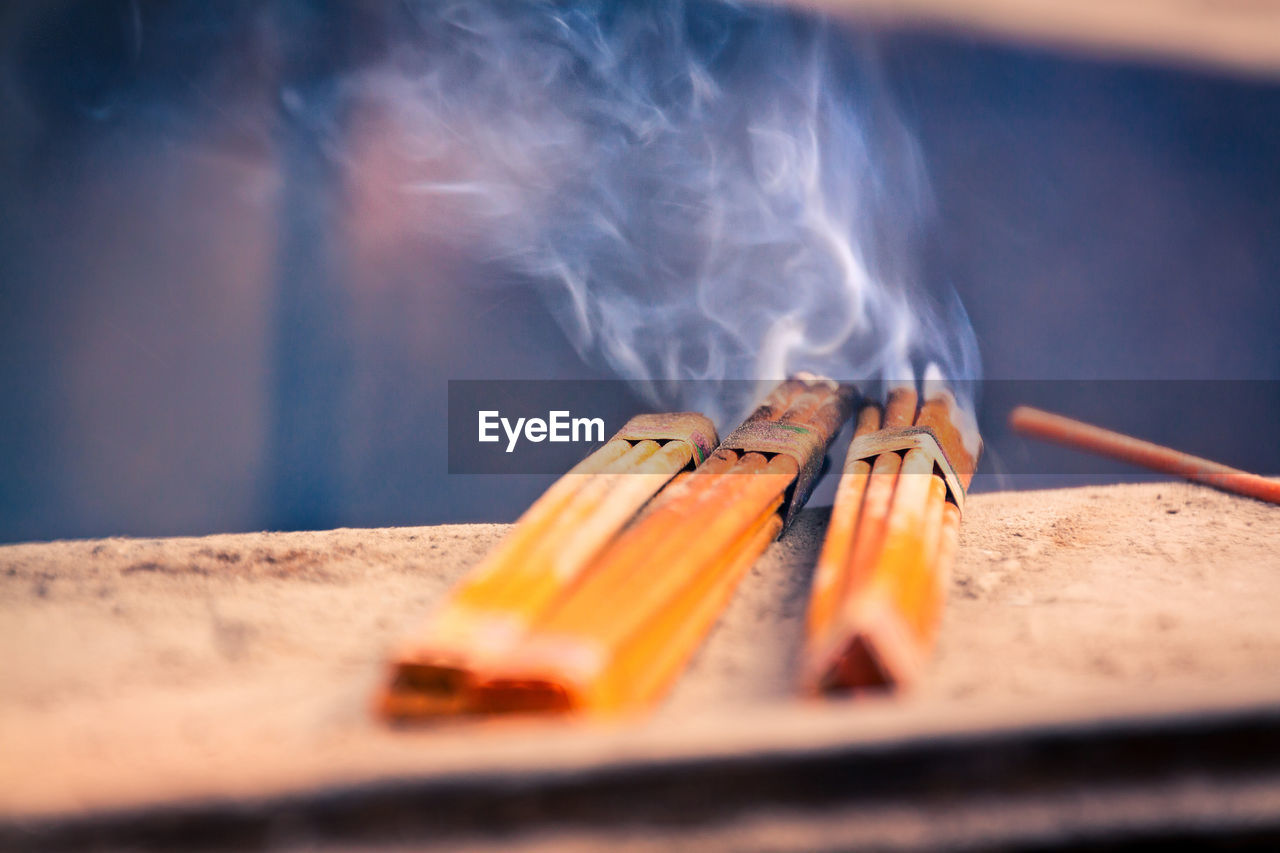 Close-up of incense sticks burning on railing