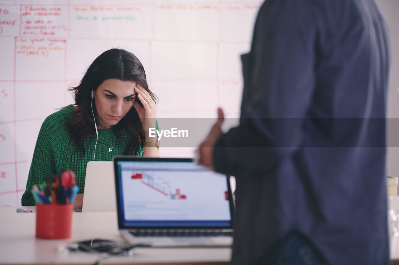 Tensed creative businesswoman using laptop at desk in office