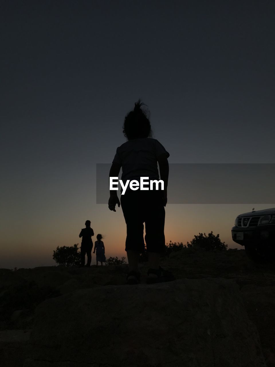 Rear view of silhouette people standing on street against sky during sunset