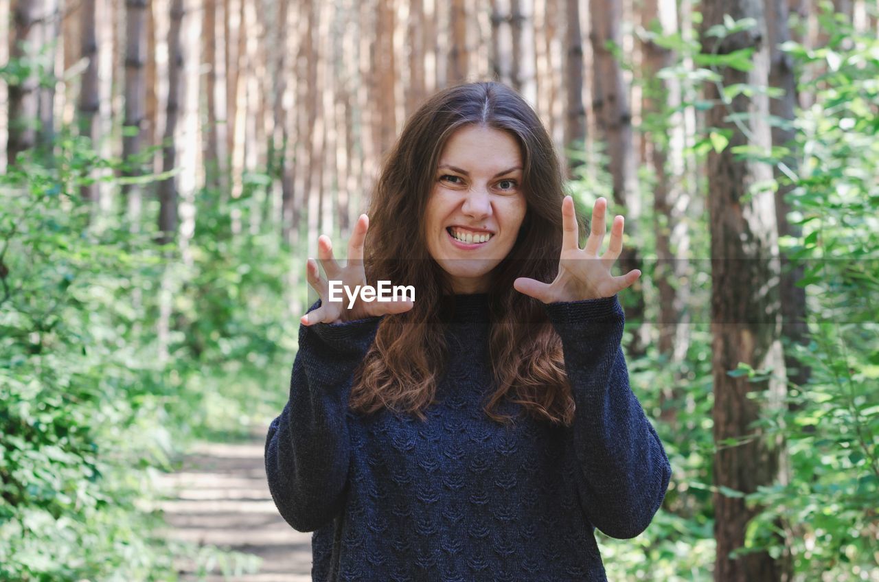 Portrait of woman making face while standing in forest