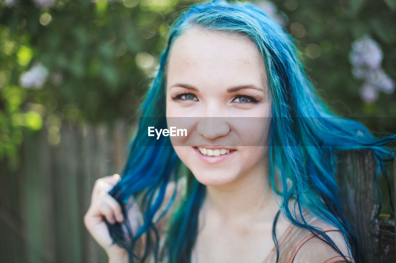 PORTRAIT OF SMILING YOUNG WOMAN