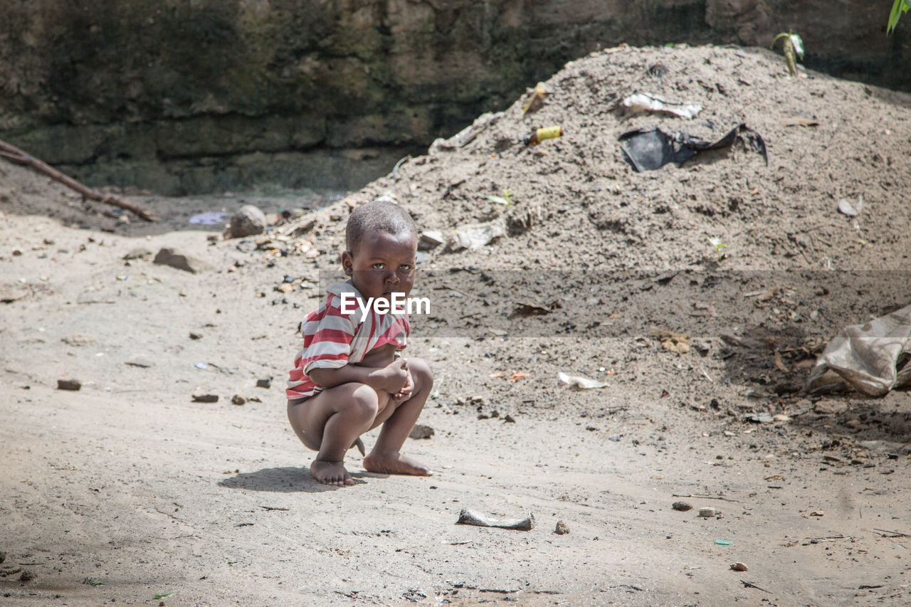 Boy crouching on road in village