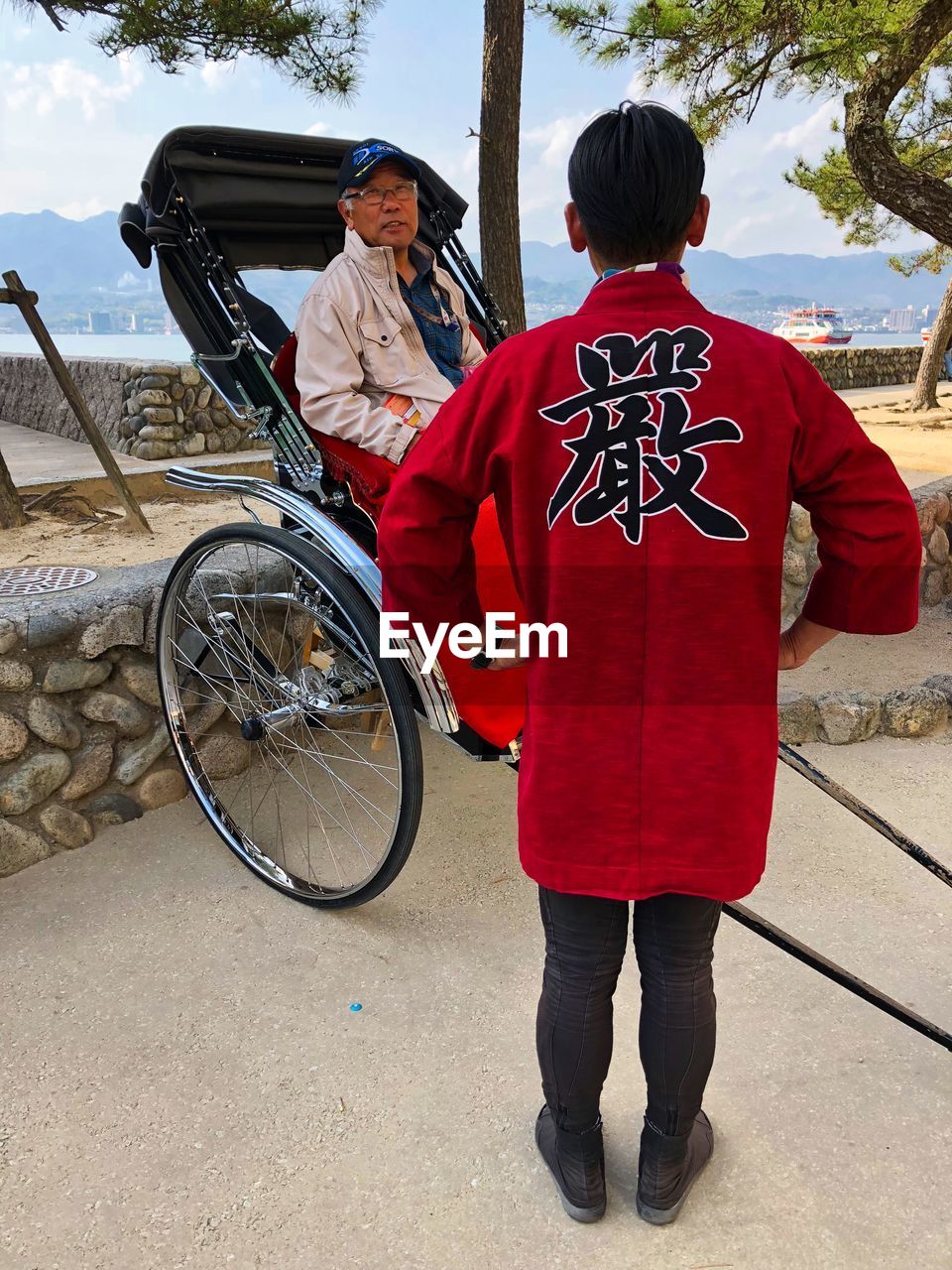 REAR VIEW OF MAN WITH BICYCLE ON ROAD