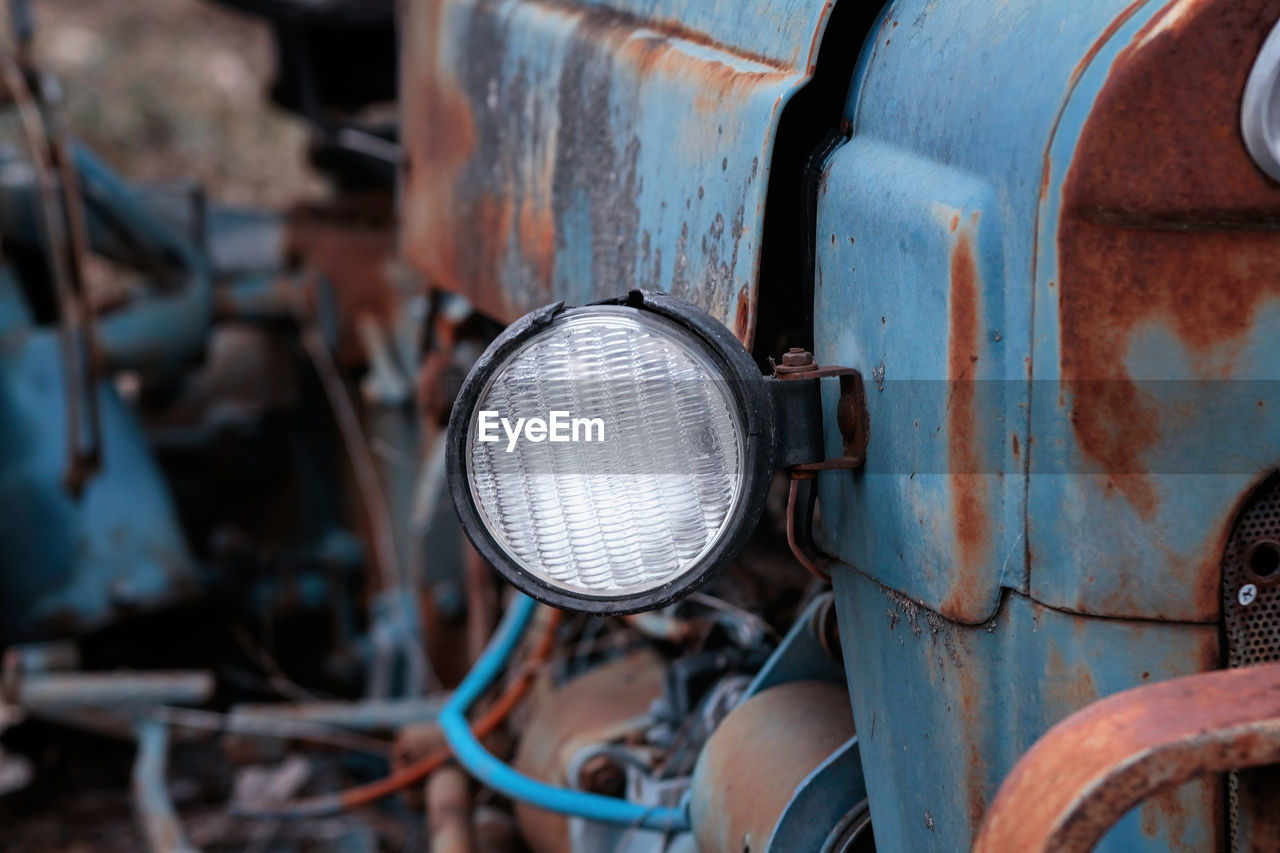 Close up of headlight of abandoned rusty vintage tractor.