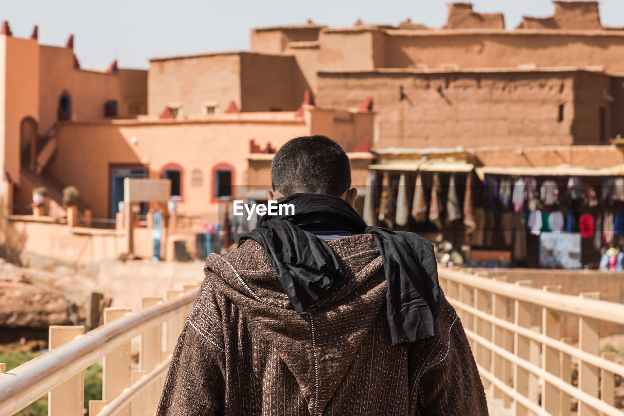 Rear view of man standing on bridge in city