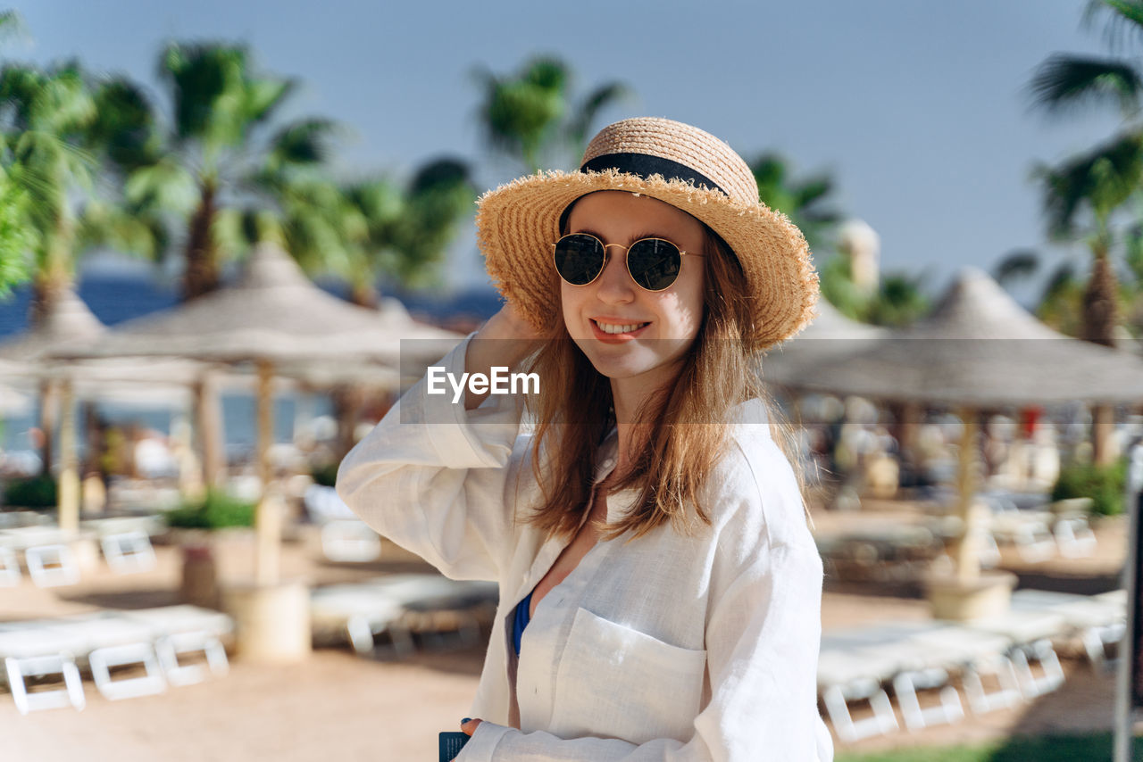 PORTRAIT OF SMILING YOUNG WOMAN IN HAT