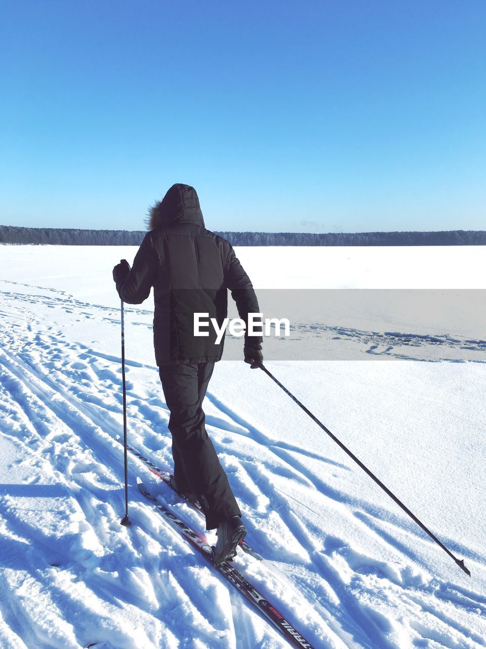 Person skiing on snow covered landscape against clear blue sky