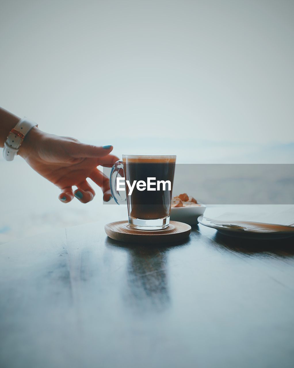 Close-up of hand holding coffee cup on table