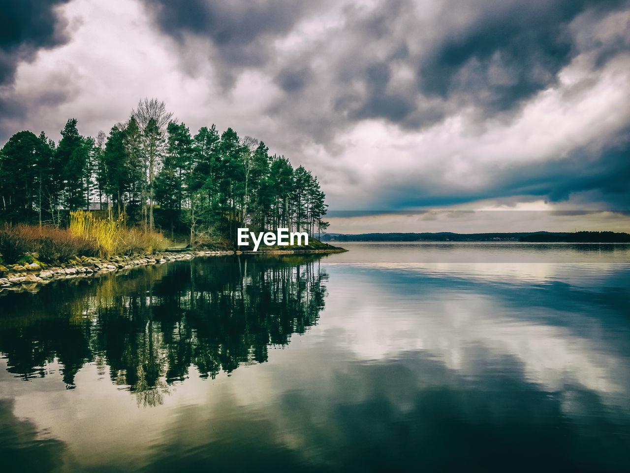 Scenic view of calm lake against cloudy sky