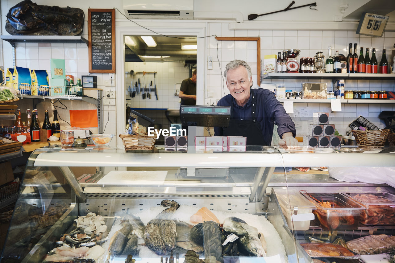 Portrait of smiling male owner standing at counter in store