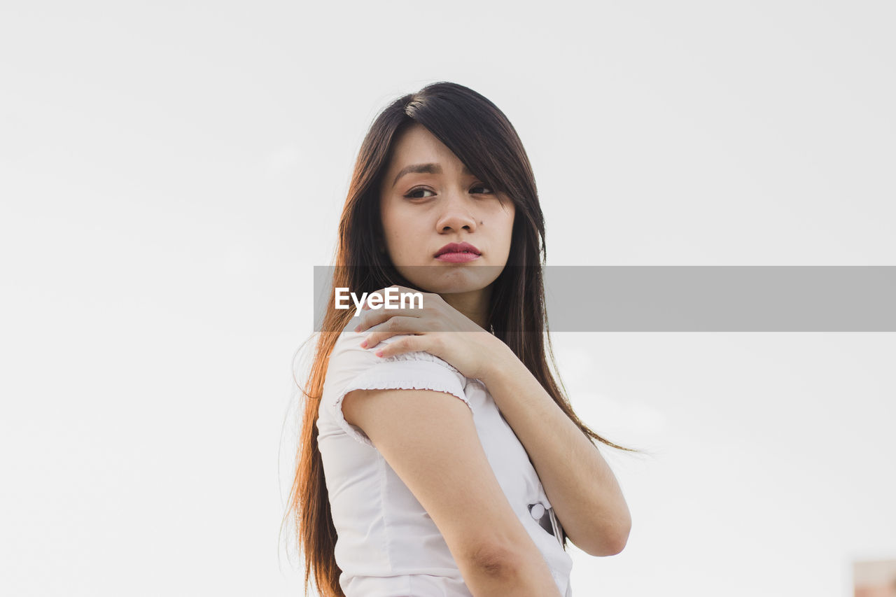 Thoughtful young woman standing against white background