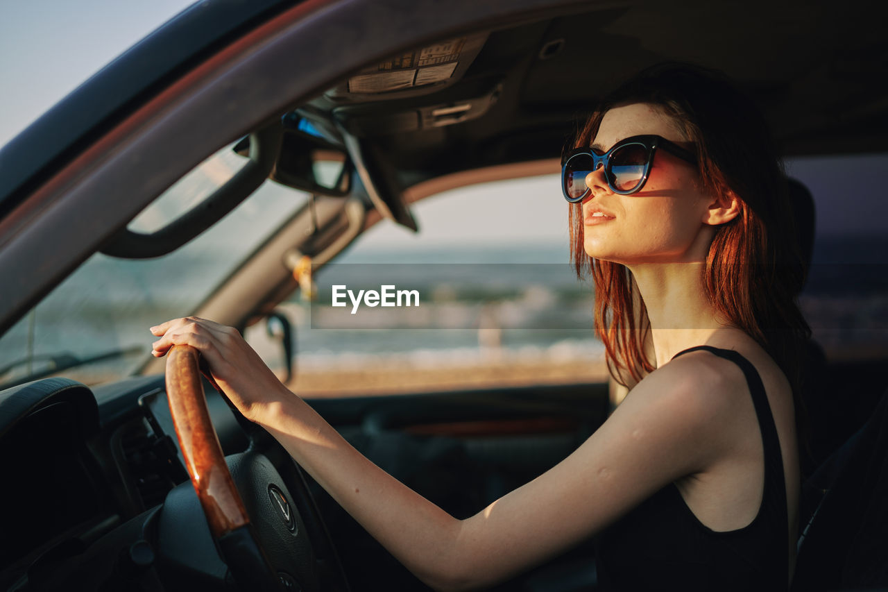 portrait of young woman wearing sunglasses while sitting in car