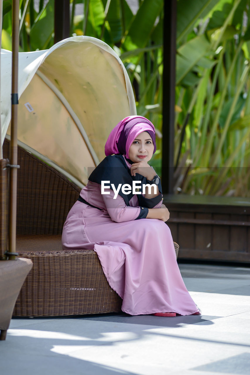 Portrait of woman looking away while sitting outdoors