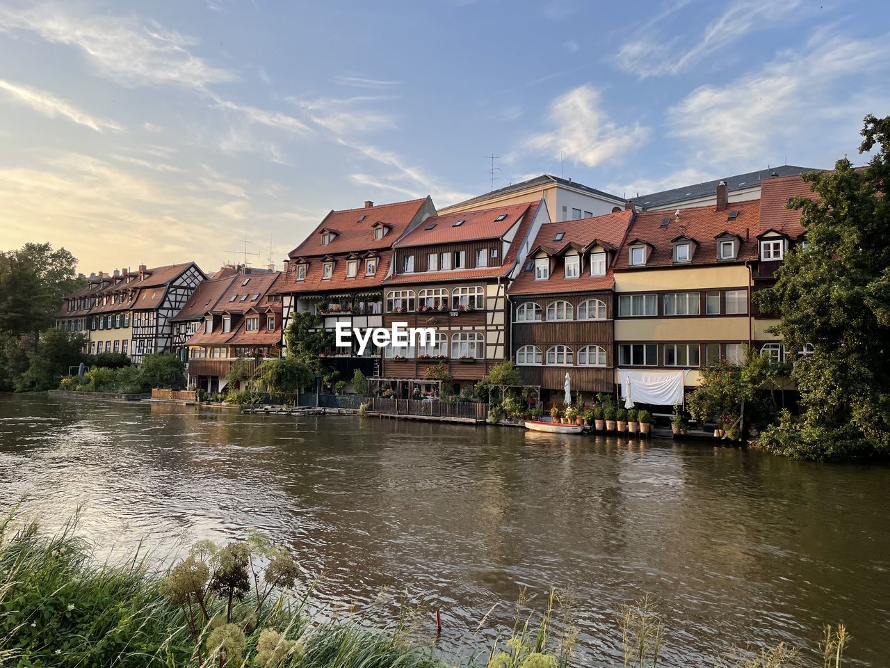 Buildings by river against sky