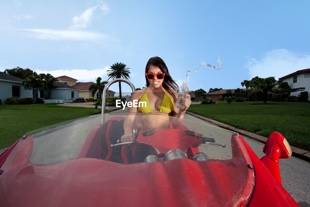 Portrait of angry young woman crushing water bottle while sitting in car