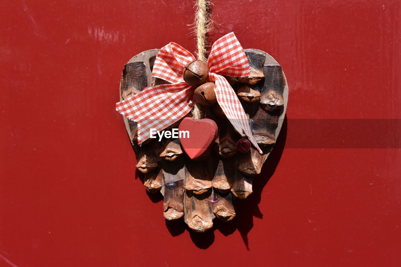 Close-up of pine cone with heart shape hanging on wall