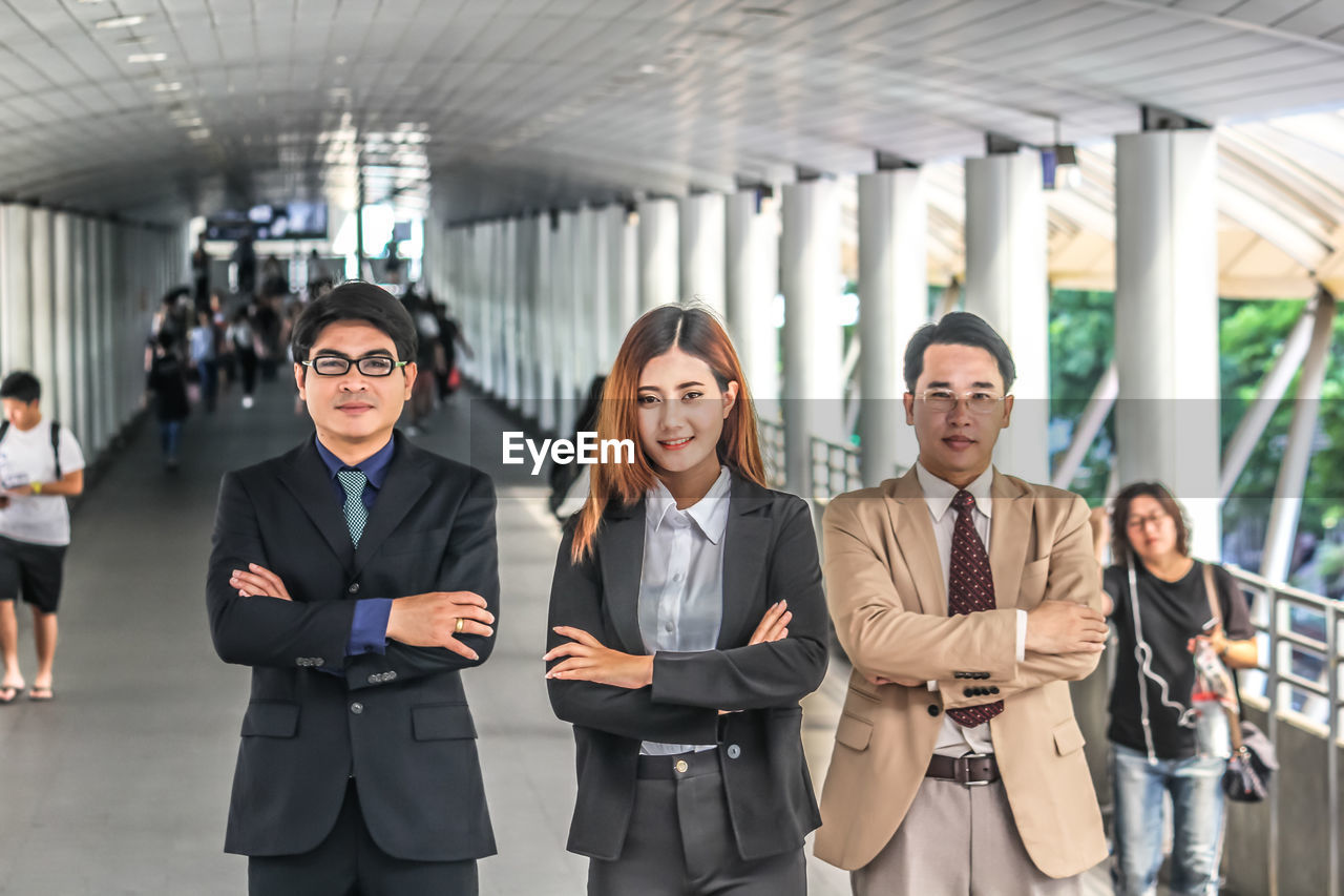 Portrait of colleagues with arms crossed standing on bridge in city