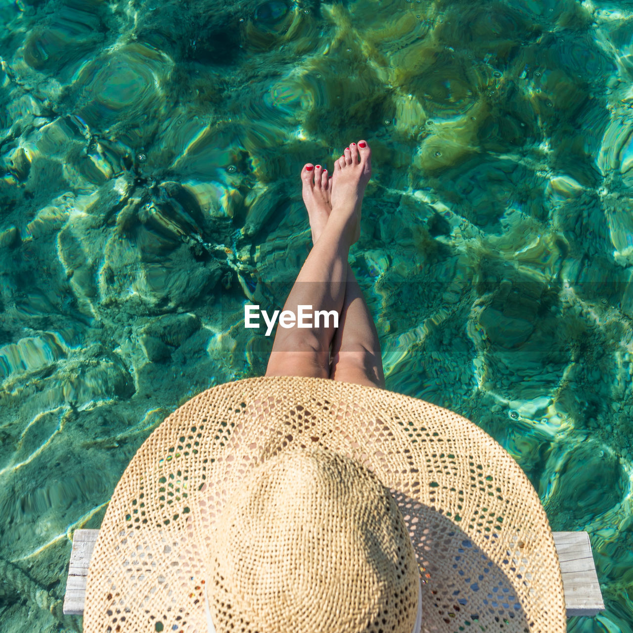 Directly above shot of woman wearing hat sitting by sea