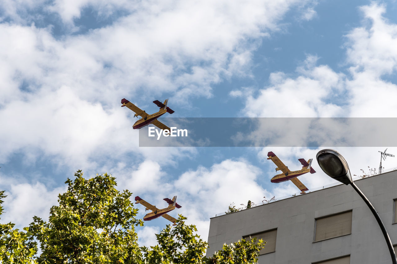 LOW ANGLE VIEW OF AIRPLANE FLYING OVER TREE AGAINST SKY