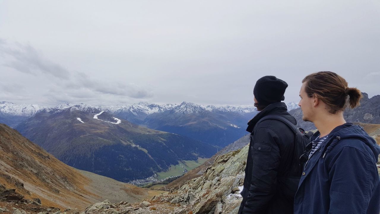 Man and woman looking at mountains against sky