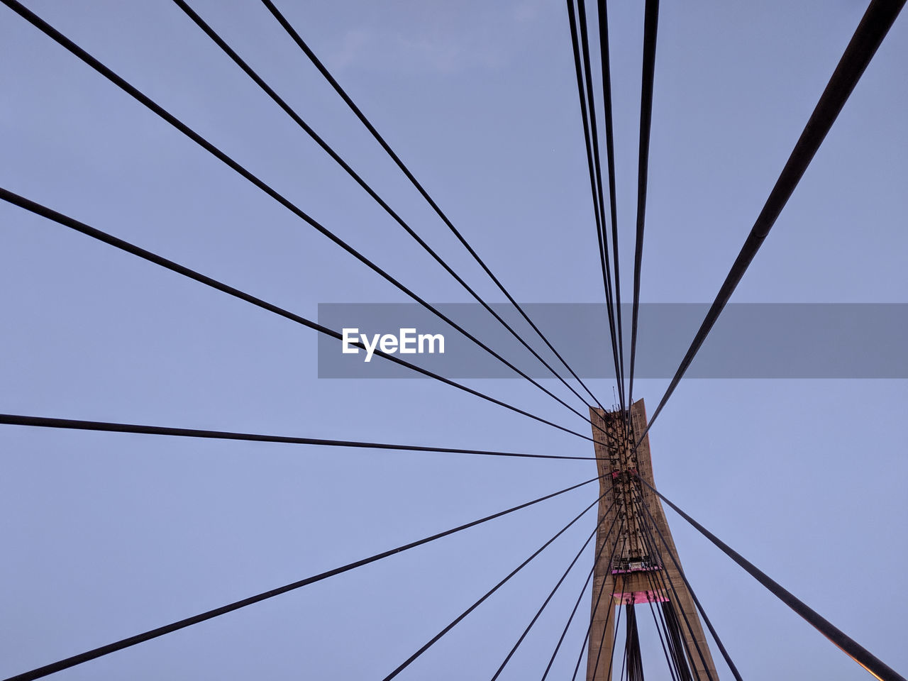 Low angle view of cables and bridge pylon against sky
