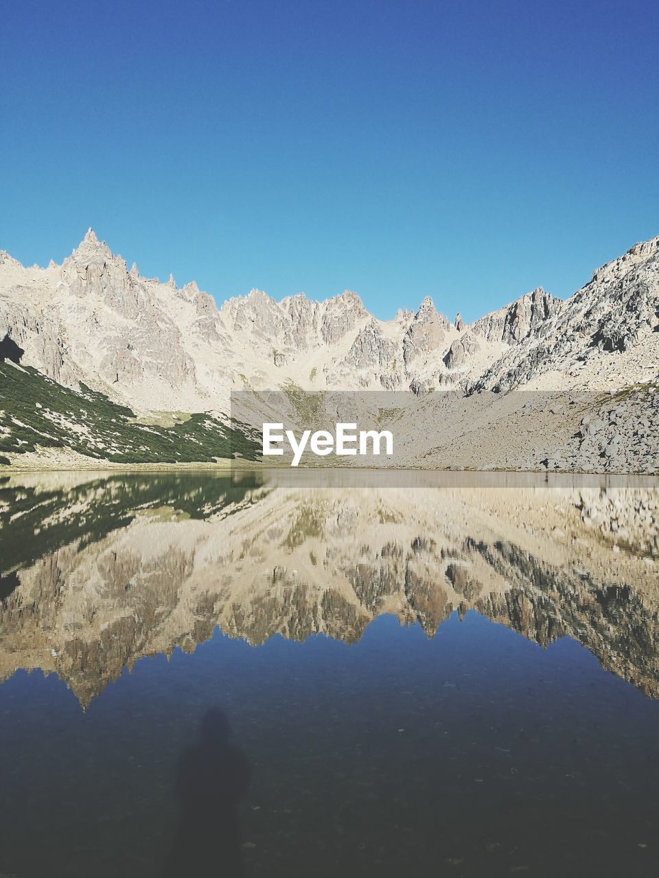 Scenic view of lake and mountains against clear blue sky