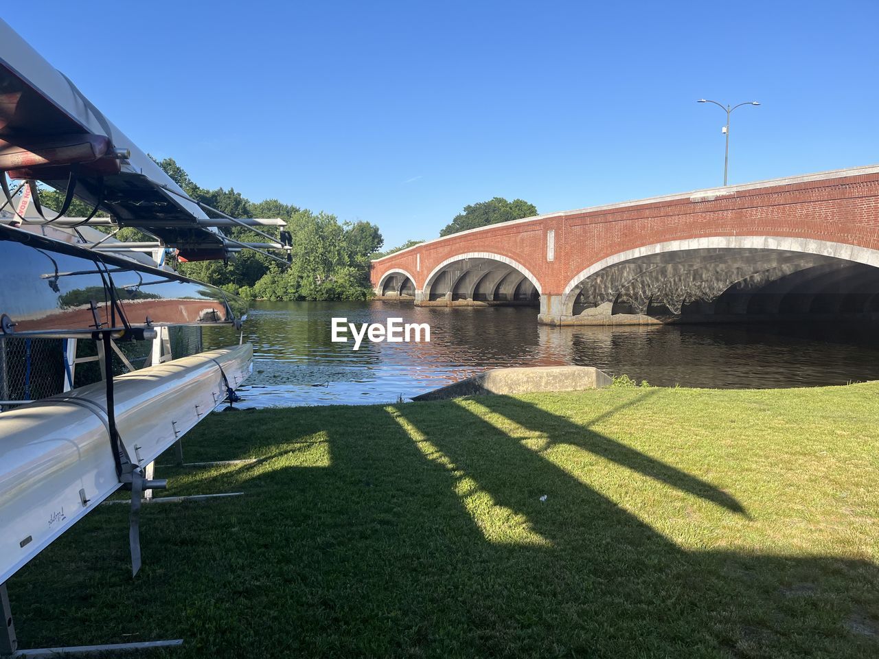 architecture, built structure, water, nature, bridge, sunlight, sky, building exterior, transportation, arch, shadow, plant, clear sky, day, sunny, no people, grass, blue, travel destinations, river, arch bridge, waterway, outdoors, travel, building, city