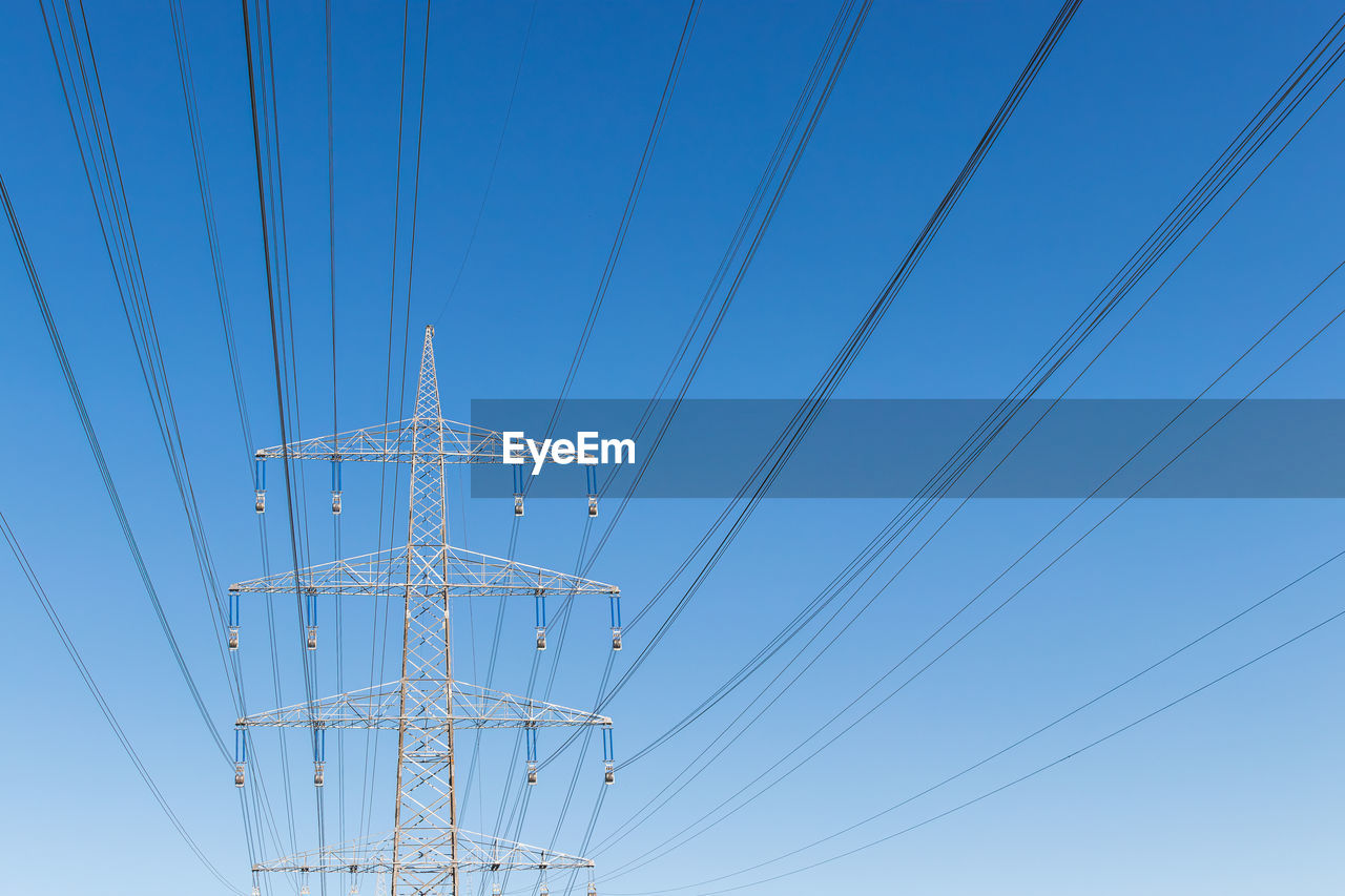 High voltage power pylon and cables - low angle view of cables against sky