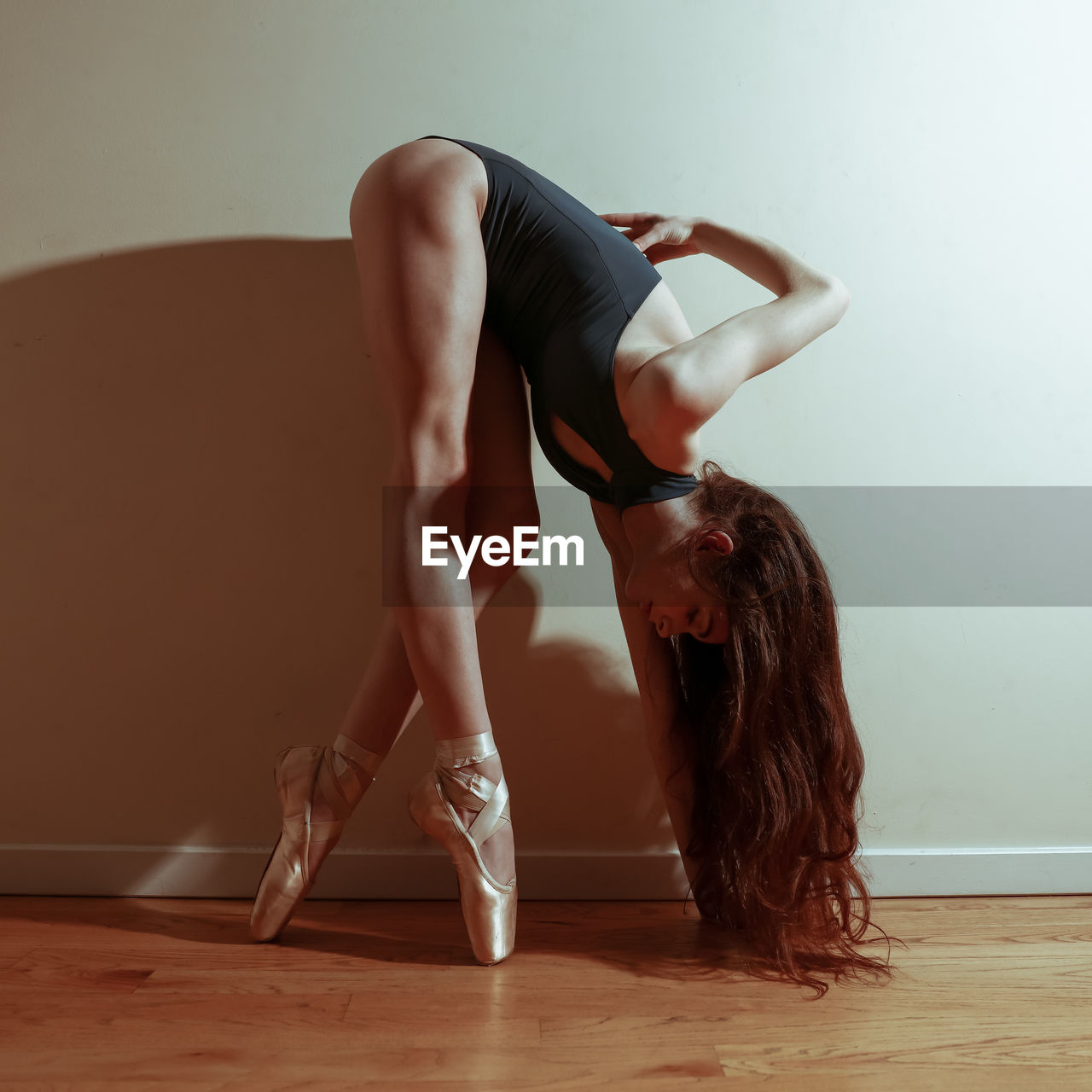 MIDSECTION OF WOMAN WITH ARMS RAISED AGAINST WALL