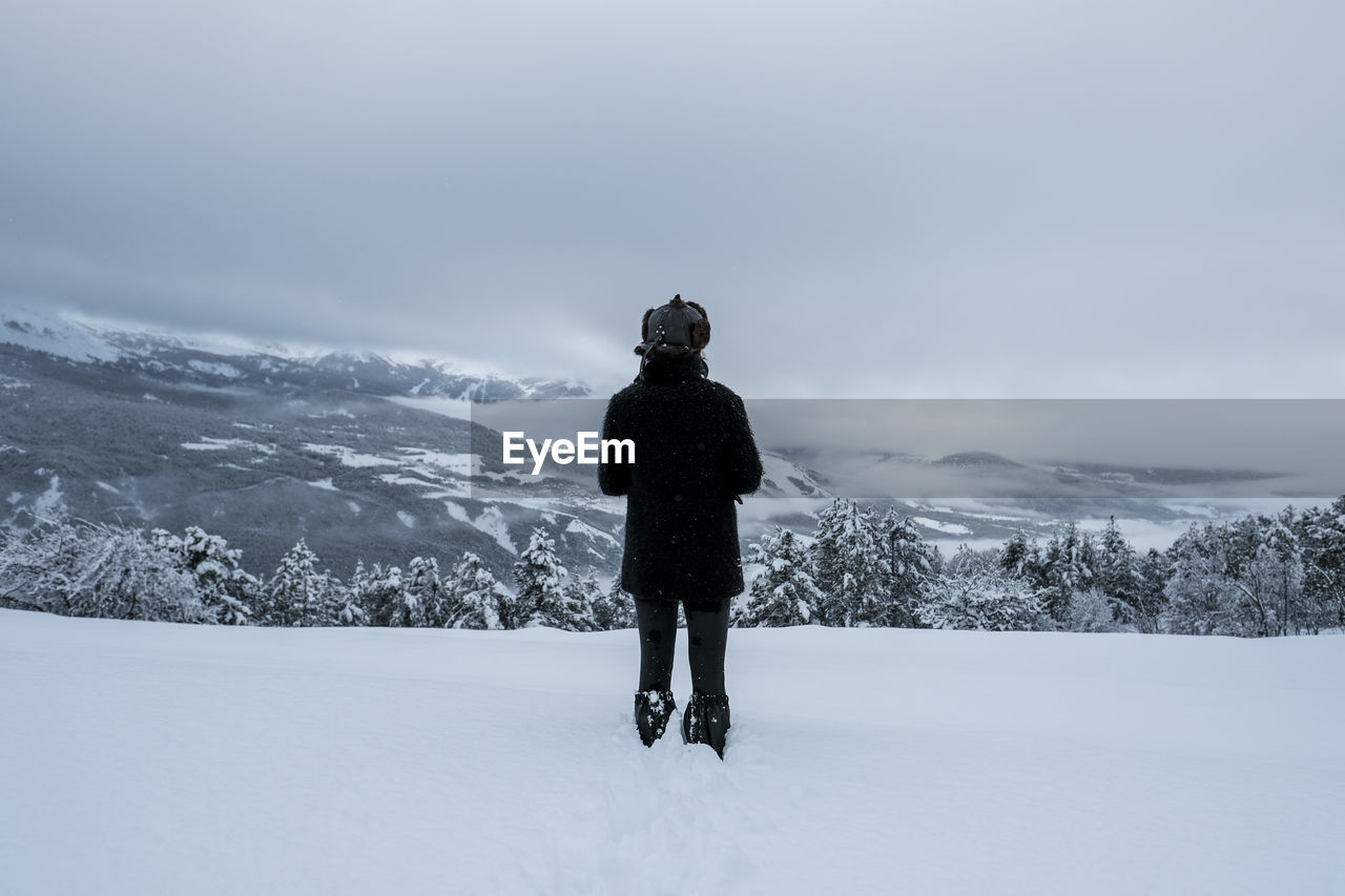 Rear view of person standing on snow field against sky