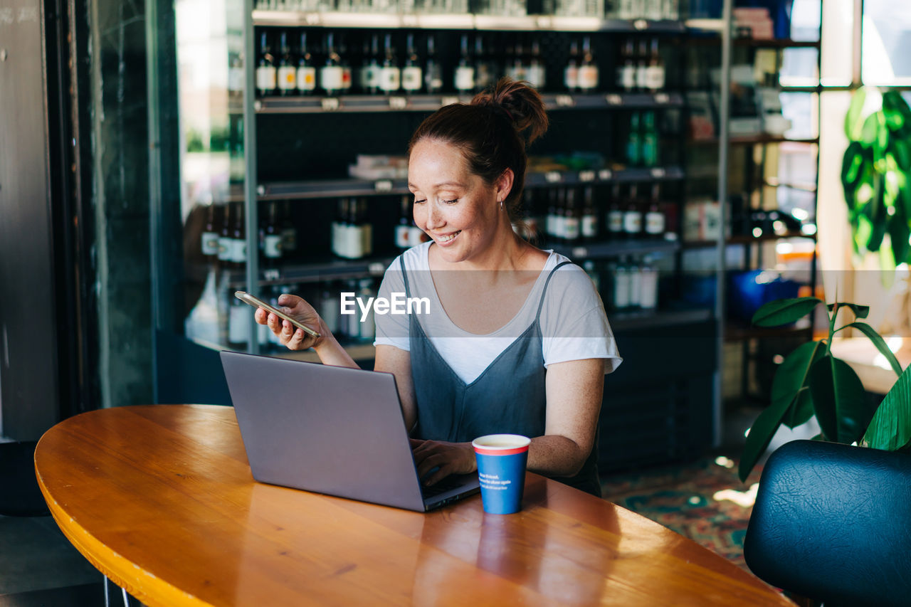 Woman using mobile phone while sitting on table