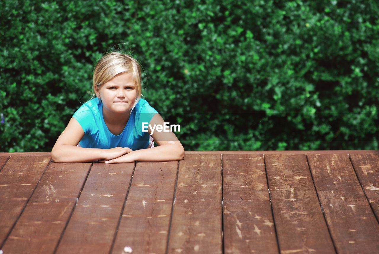 Portrait of girl sitting on wood