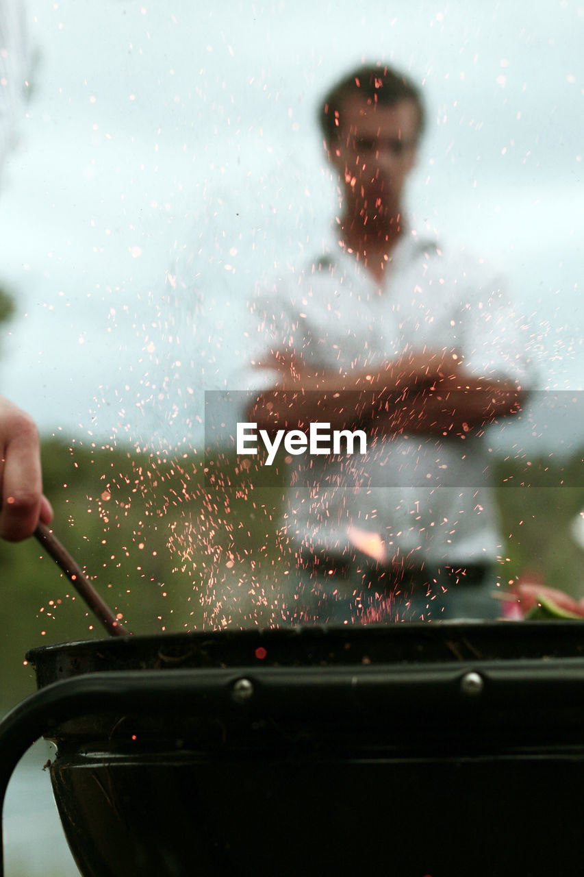 Close-up of hand preparing food on barbecue