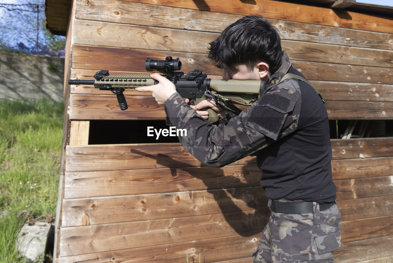 A young soldier stationed behind a shed