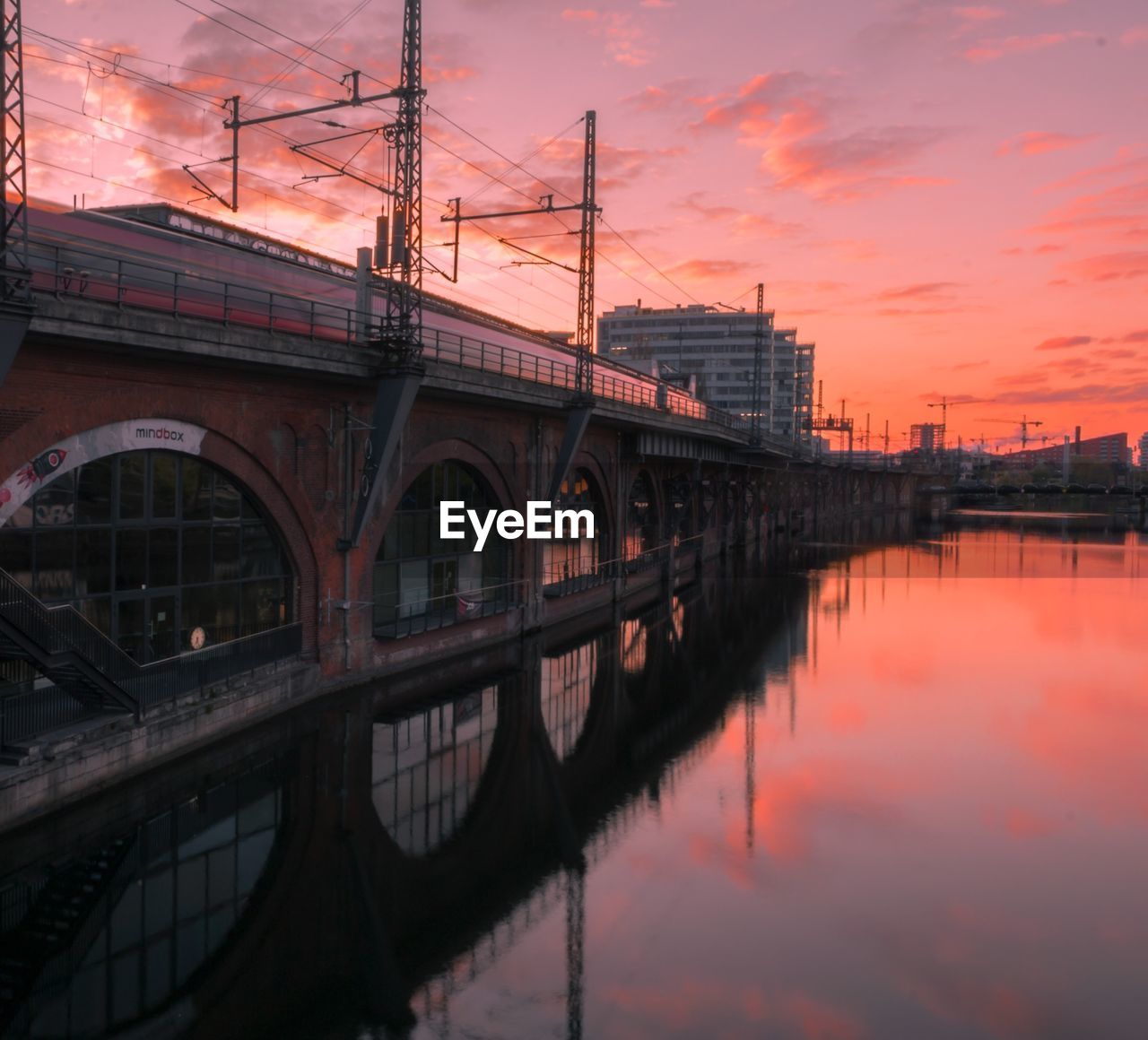 BRIDGE OVER RIVER AGAINST ORANGE SKY