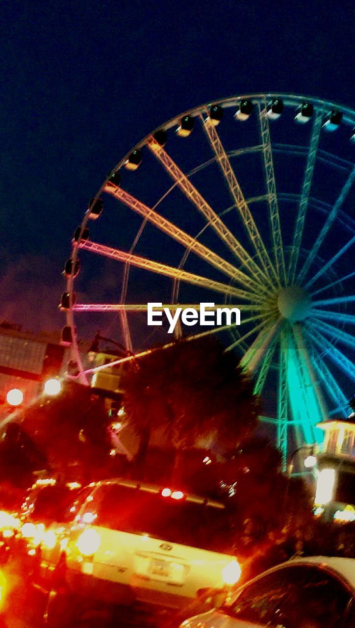 LOW ANGLE VIEW OF ILLUMINATED FERRIS WHEEL AGAINST SKY