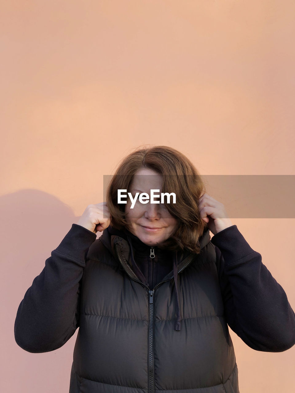 Portrait of woman standing against gray background