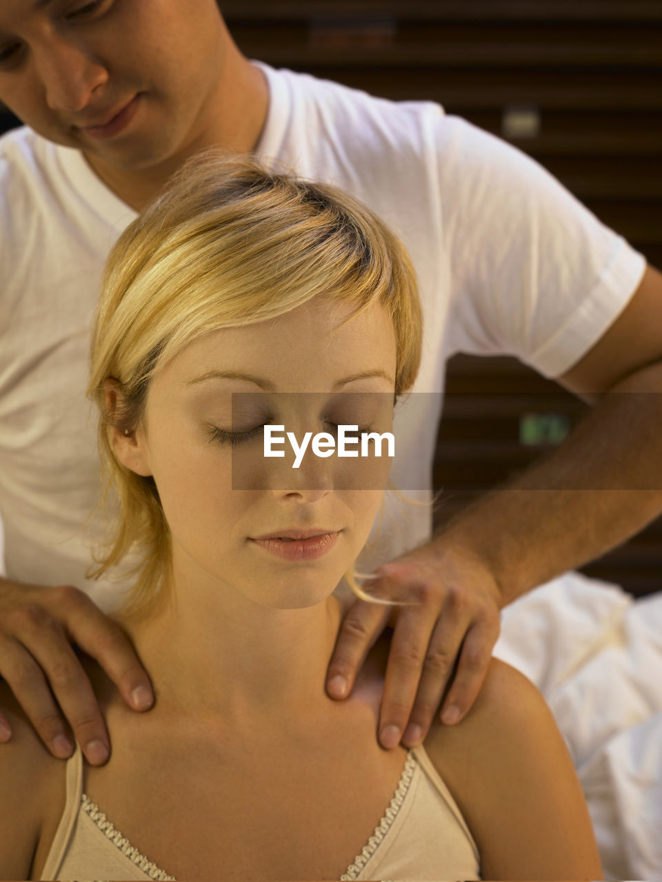 Boyfriend giving massage to girlfriend on bed at home