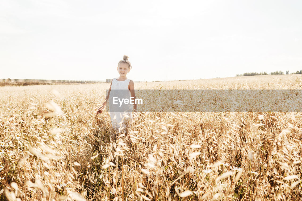 Portrait of cute girl standing in farm against sky