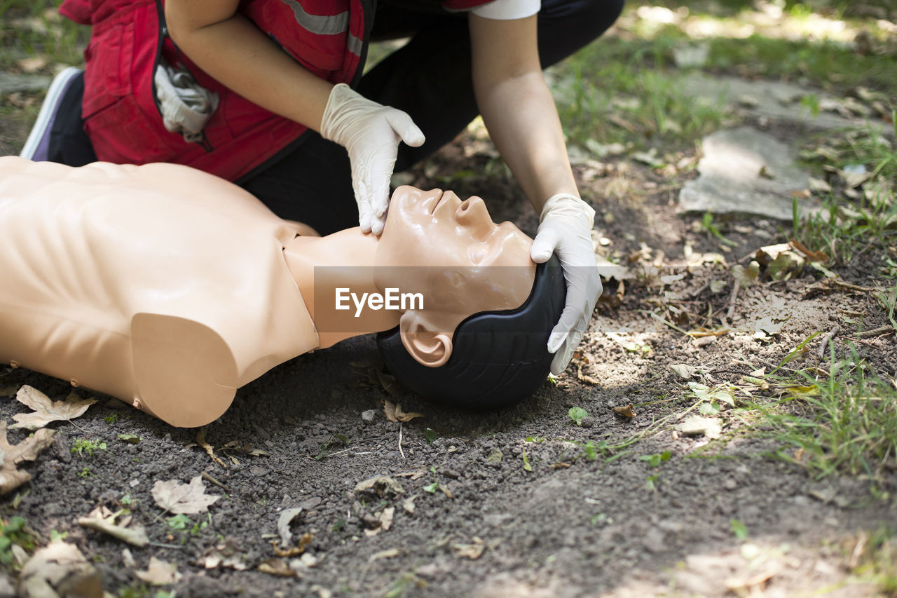 Low section of man practicing cpr on dummy at field