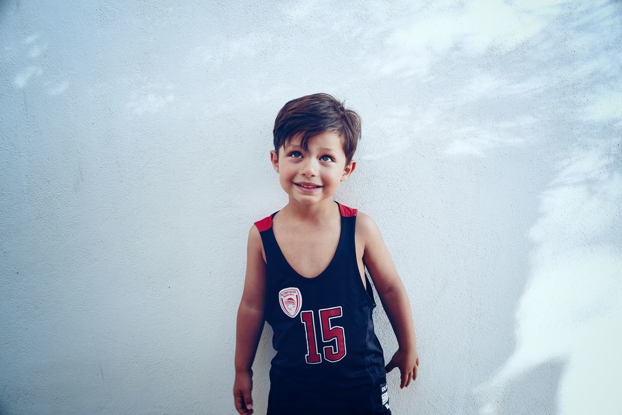 Smiling boy standing against white wall