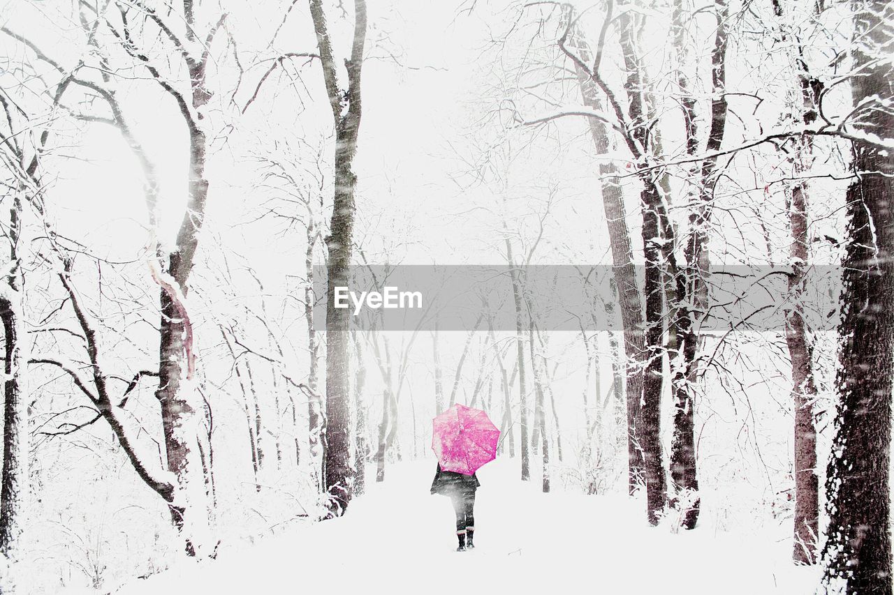 WOMAN STANDING ON SNOW COVERED LANDSCAPE